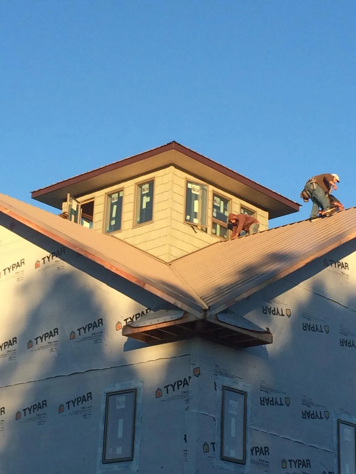 Roofers working around a rooftop cupola on a new metal roof at sunset — Roof Waterproofing in Hardin by Roofing Brothers